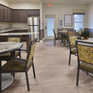 A modern kitchen and dining area with tables and chairs, featuring a stainless steel refrigerator.
