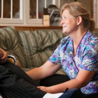 A caregiver smiling while attending to a patient at home.