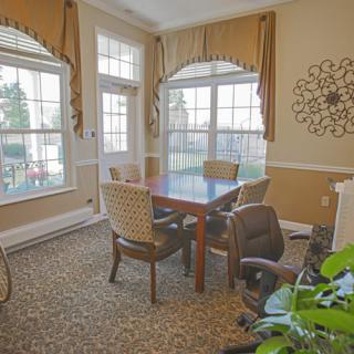 A cozy dining room with a table, chairs, and large windows letting in natural light.