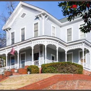 A historic Victorian-style house with a charming porch and an American flag flying out front.