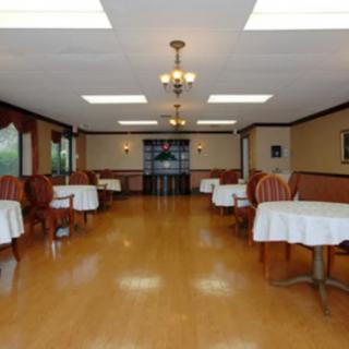 An empty dining room with neatly arranged tables and chairs, featuring elegant lighting and hardwood flooring.
