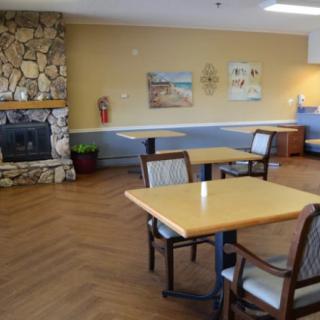 A cozy dining area with tables and chairs, featuring a stone fireplace and wall art.