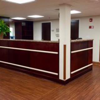A modern office reception area with a wooden desk and flooring.