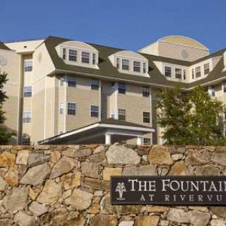 The exterior view of The Fountains at RiverVue, featuring a stone wall and signage.