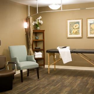 A serene massage room with a comfortable massage table, cozy chairs, and warm lighting.