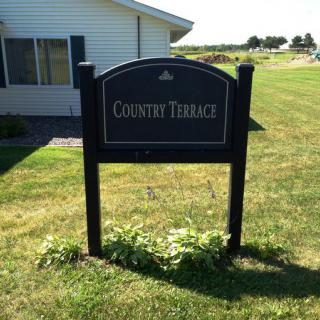 Sign for Country Terrace in front of a building and lawn.