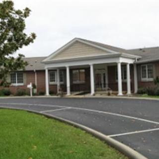 A view of the entrance to a well-maintained building with a landscaped parking area.