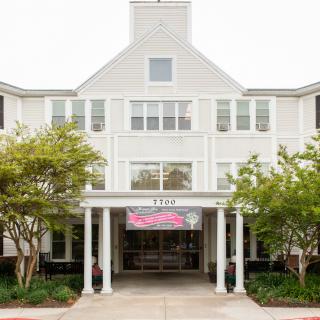 A large white building with an inviting entrance and surrounding trees.