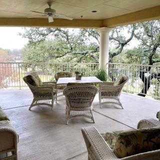 A cozy outdoor patio featuring wicker furniture and a dining table, surrounded by trees.