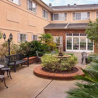 A charming courtyard with a central fountain, surrounded by benches and lush greenery.
