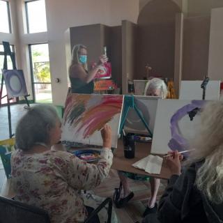 A group of people participating in an art class, painting colorful designs on canvases.