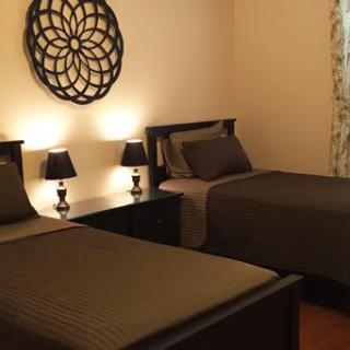 A cozy bedroom with twin beds, featuring warm lighting and elegant wall decor.
