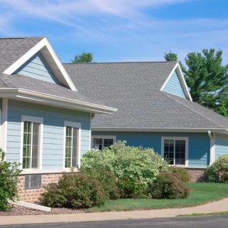 A charming suburban house with well-maintained landscaping and a clear blue sky.
