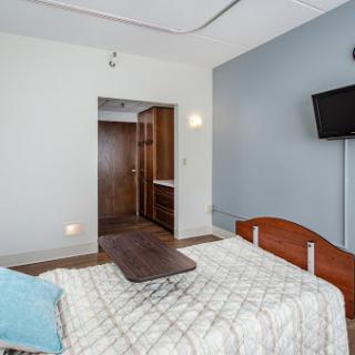 A cozy and modern bedroom featuring a wooden bed and a wall-mounted television.