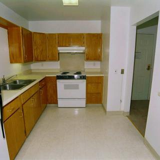 An empty kitchen with wooden cabinets and modern appliances.