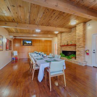 A cozy dining room with a wooden ceiling, featuring a long table, chairs, and a fireplace.