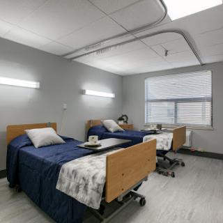 A shared patient room in a modern healthcare facility, featuring two hospital beds and a comfortable ambiance.