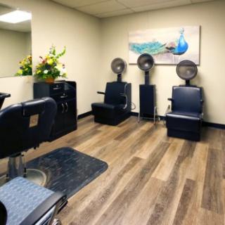 An interior view of a hair salon featuring chairs with hair dryers, hardwood flooring, and decorative elements.