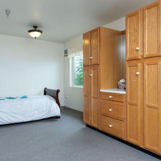 A minimalist bedroom with a bed and wooden wardrobe.
