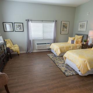 A well-decorated bedroom with twin beds featuring yellow bedding and hardwood floors.