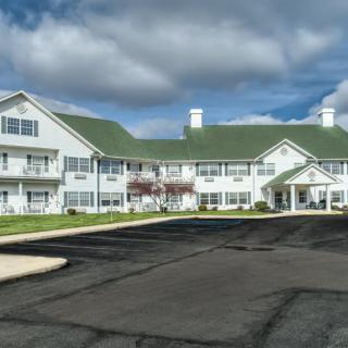 A large white residential building against a cloudy sky with a spacious parking area.