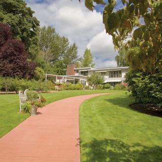 A scenic garden pathway leading to a modern building surrounded by lush greenery.