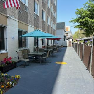 A sunny outdoor seating area with umbrellas and potted plants next to a building.