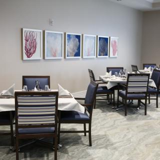 A cozy restaurant dining area with neatly arranged tables and chairs, adorned with artwork on the walls.