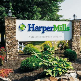 Entrance sign for Harper Mills surrounded by plants and stone pillars.