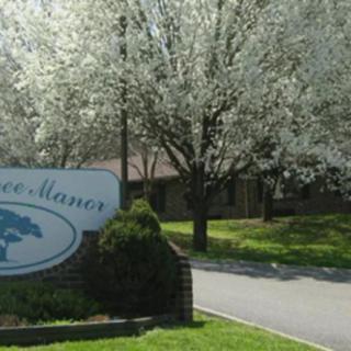 A roadside sign with blooming trees and greenery in the background.