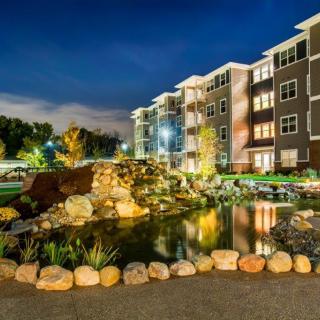 A beautifully lit apartment complex with a serene pond at night.