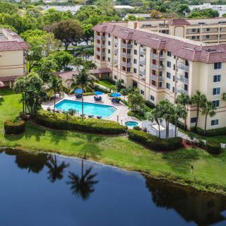 Aerial view of a residential apartment complex with a swimming pool and surrounding greenery near a lake.