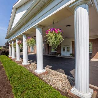 A building with white columns and hanging flower baskets along the entrance walkway.