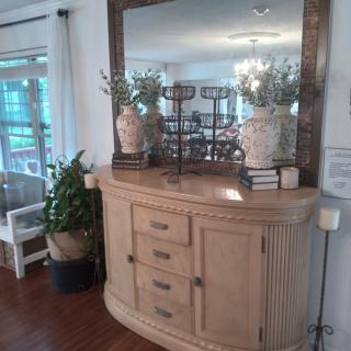 A decorated dresser with a large mirror, vases, and books in a living room setting.