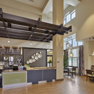 A modern and spacious lobby with high ceilings, featuring a reception desk and large windows.