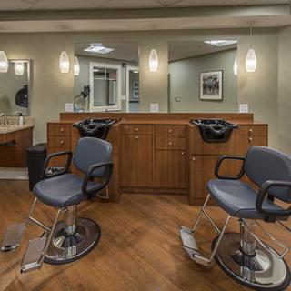 A well-lit barber shop interior with stylish chairs and mirrors.