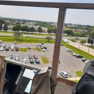 A view from a balcony overlooking a parking lot and surrounding landscape.