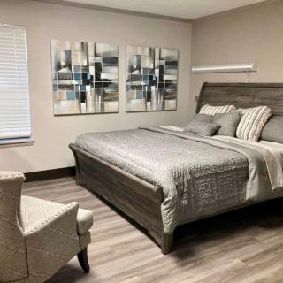 A modern bedroom with gray tones, featuring a comfortable bed and abstract artwork on the wall.