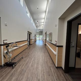 A well-lit corridor in a modern medical facility, featuring clean lines and a wooden floor.