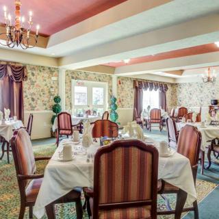 An elegant dining room with beautifully set tables, chandeliers, and ornate decor.
