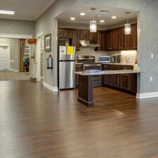 A modern kitchen with an open layout, featuring dark wood cabinetry and sleek appliances.