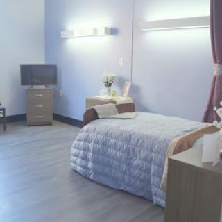 A serene and modern bedroom with soft blue walls and minimalist furniture.