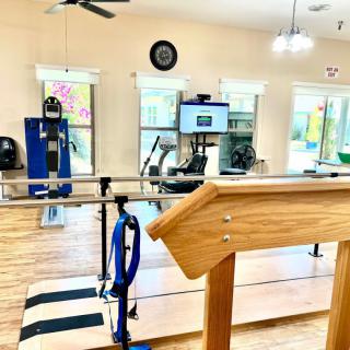 A well-equipped rehabilitation and physical therapy room with parallel bars and exercise machines.