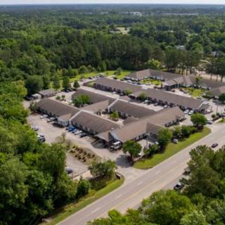 Aerial view of a residential housing complex surrounded by trees and a parking lot.
