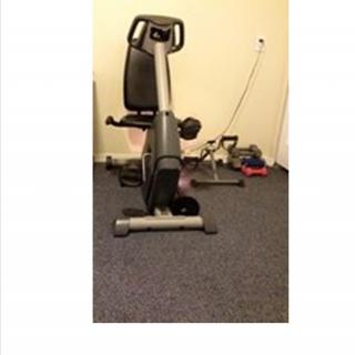 A stationary exercise bike positioned on a carpeted floor in a home setting.