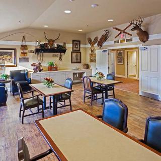 A cozy dining room with several tables and chairs, featuring warm decorations and wooden flooring.