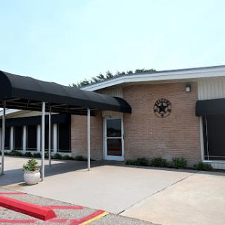 An exterior view of a commercial building featuring a covered entrance and parking area.