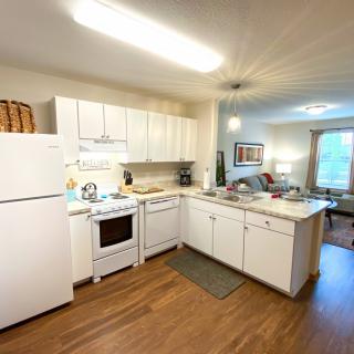 A cozy kitchen with white cabinetry, a refrigerator, and a stove in an apartment setting.