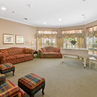 A cozy living room with comfortable seating, a piano, and large windows that let in natural light.