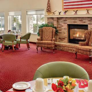 A cozy dining area with a fireplace, featuring chairs and tables on a red carpet.